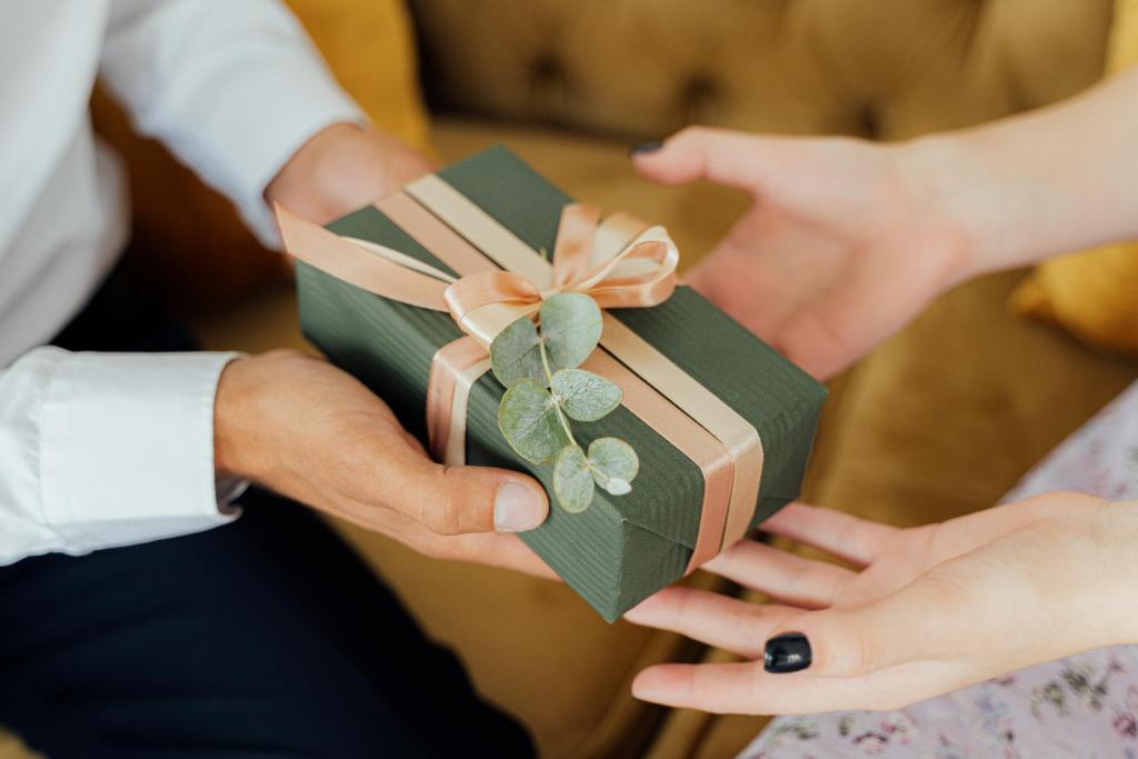 2 pair of hands, exchanging a gift box.